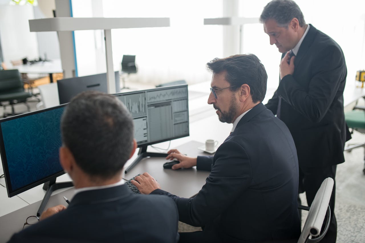 services-01 Colleagues in a modern office reviewing stock market trends and data on multiple screens.